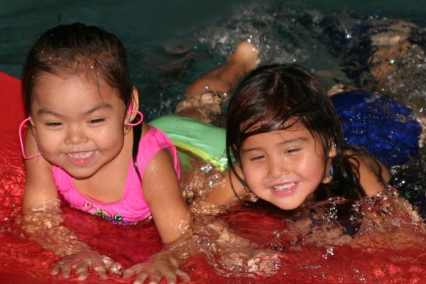 A Child and Youth Care First Nations Worker taking care of two little girls who are having fun at the pool