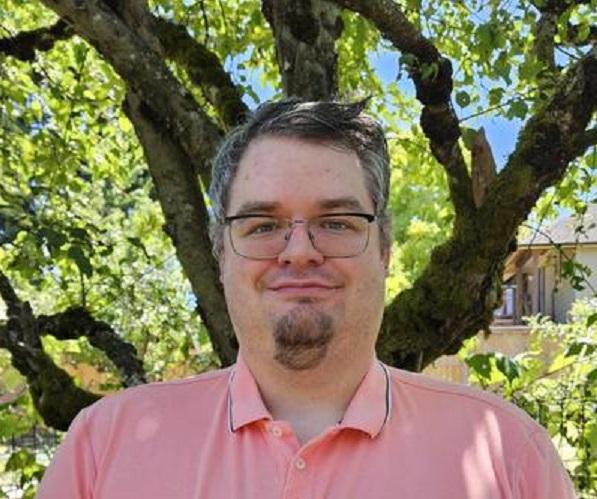 Smiling man wearing glasses and a pink polo shirt