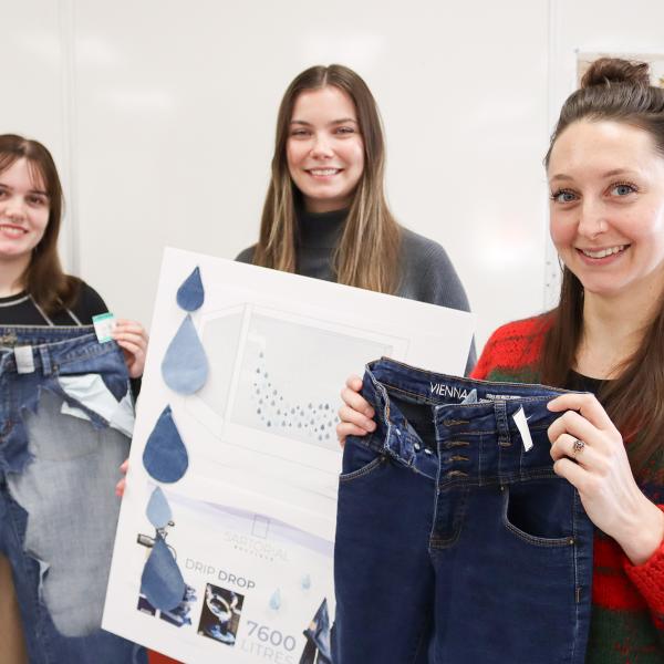 From left, Shayla Antonichuk, Celia Brand and Melissa Watt hold up their graphic design concept pieces.