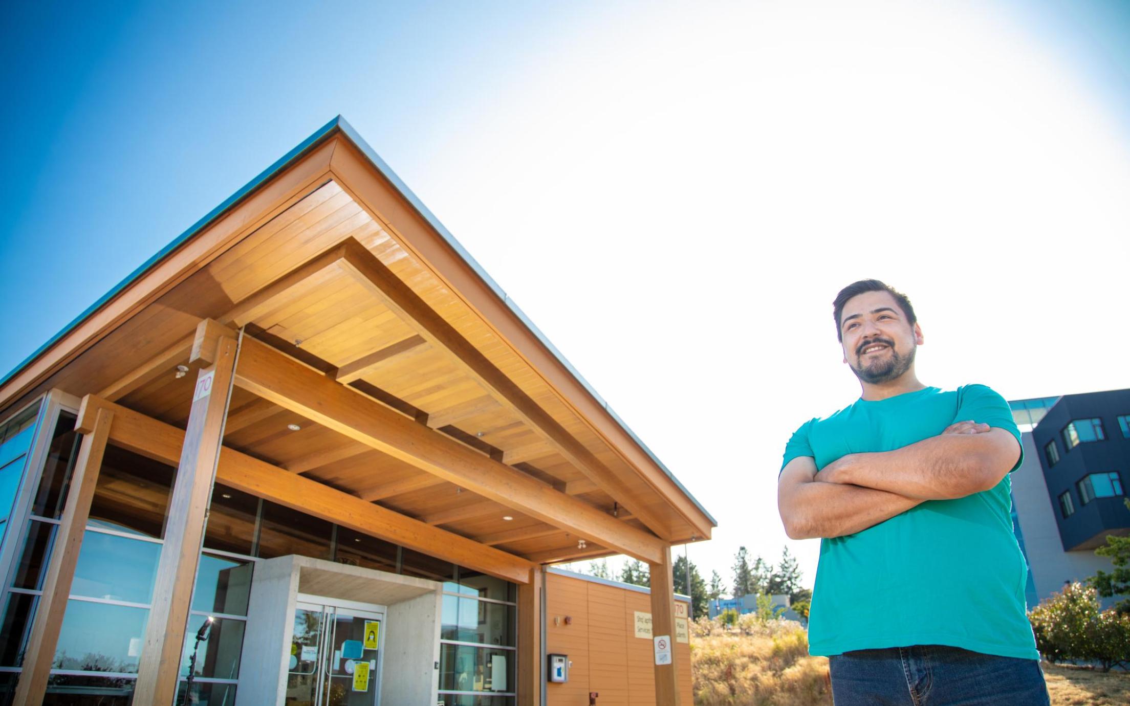 Hayden stands in front of Shq'apthut, VIU's Indigenous gathering place on the Nanaimo campus