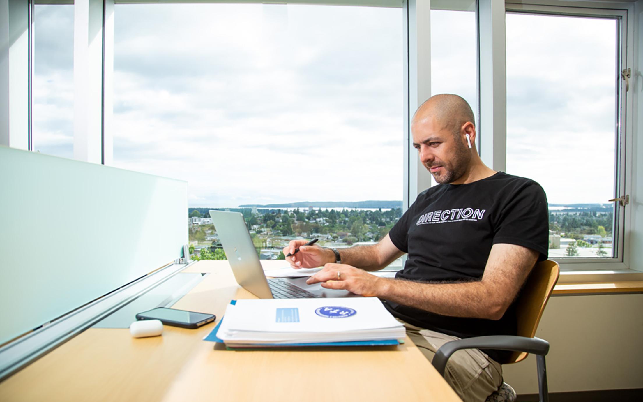 Student studies at a desk in the library with a view of the City of Nanaimo in the background