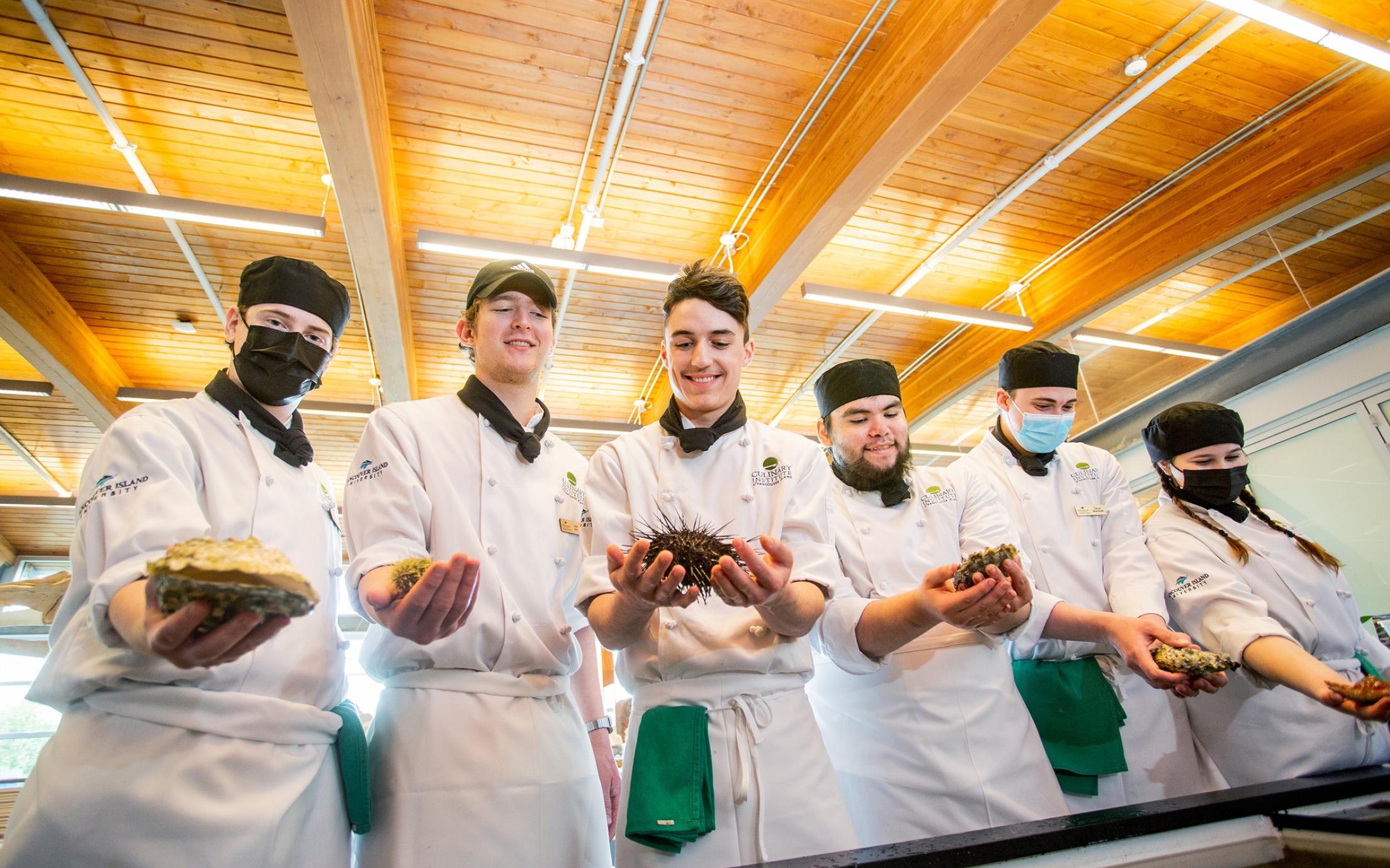 Culinary arts students hold different seafood items