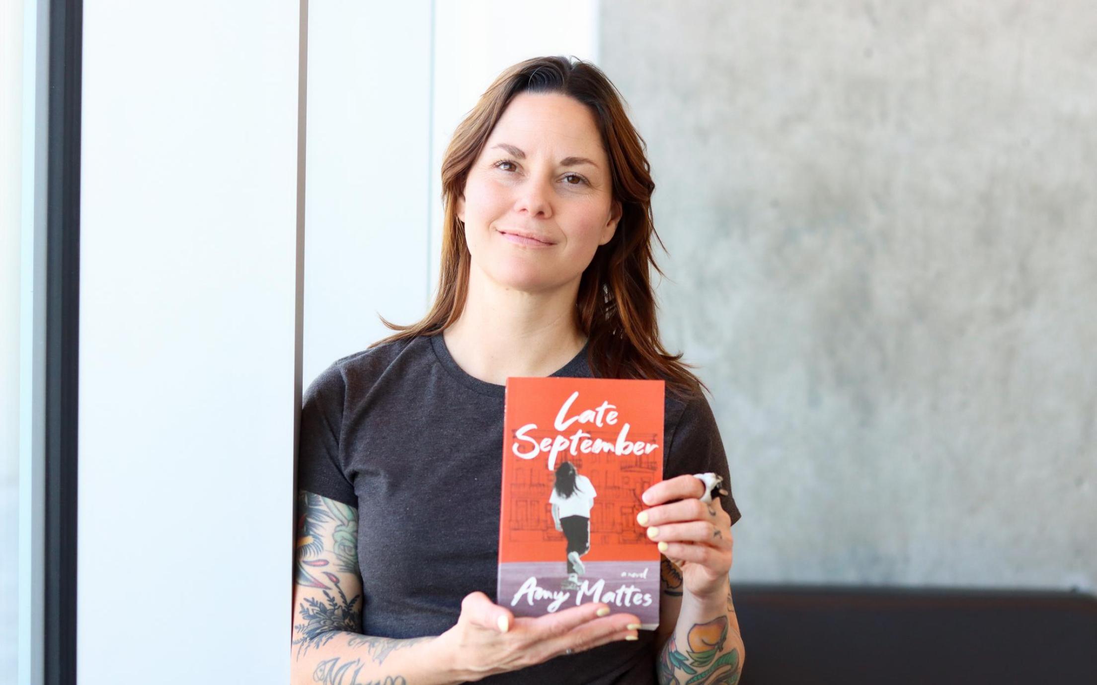 Amy Mattes holds up a copy of her book, Late September.
