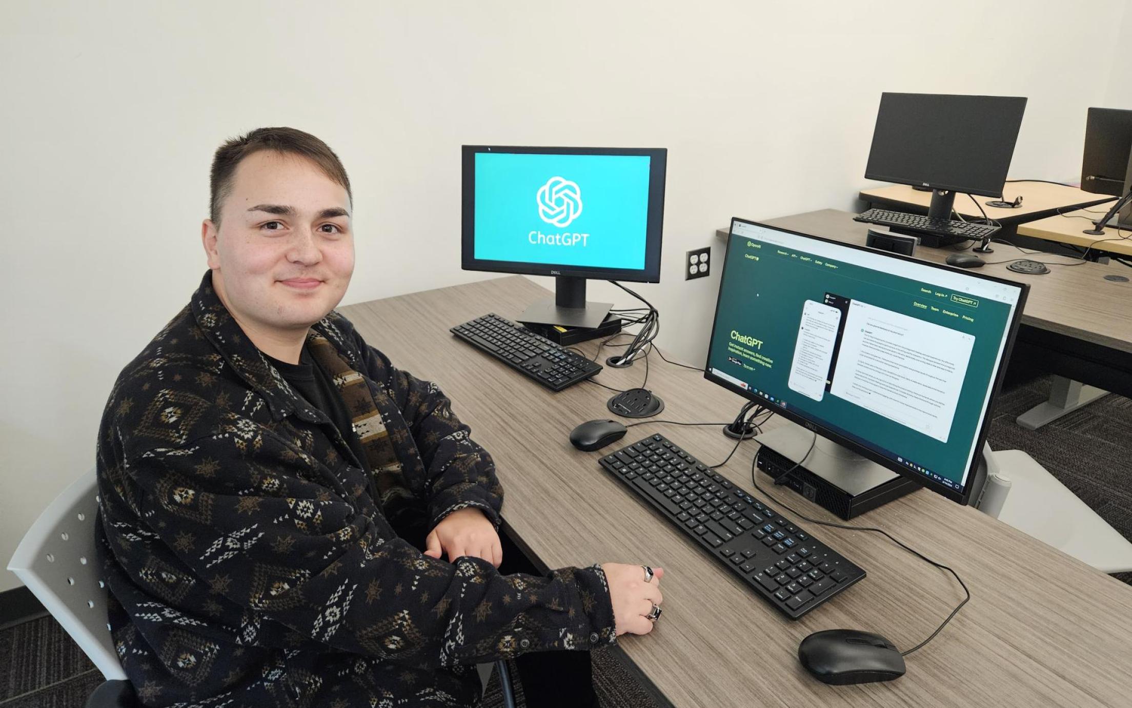 Andrew Szilagyi sitting in front of a computer and smiling at the camera. ChatGPT is on the screen in the background.