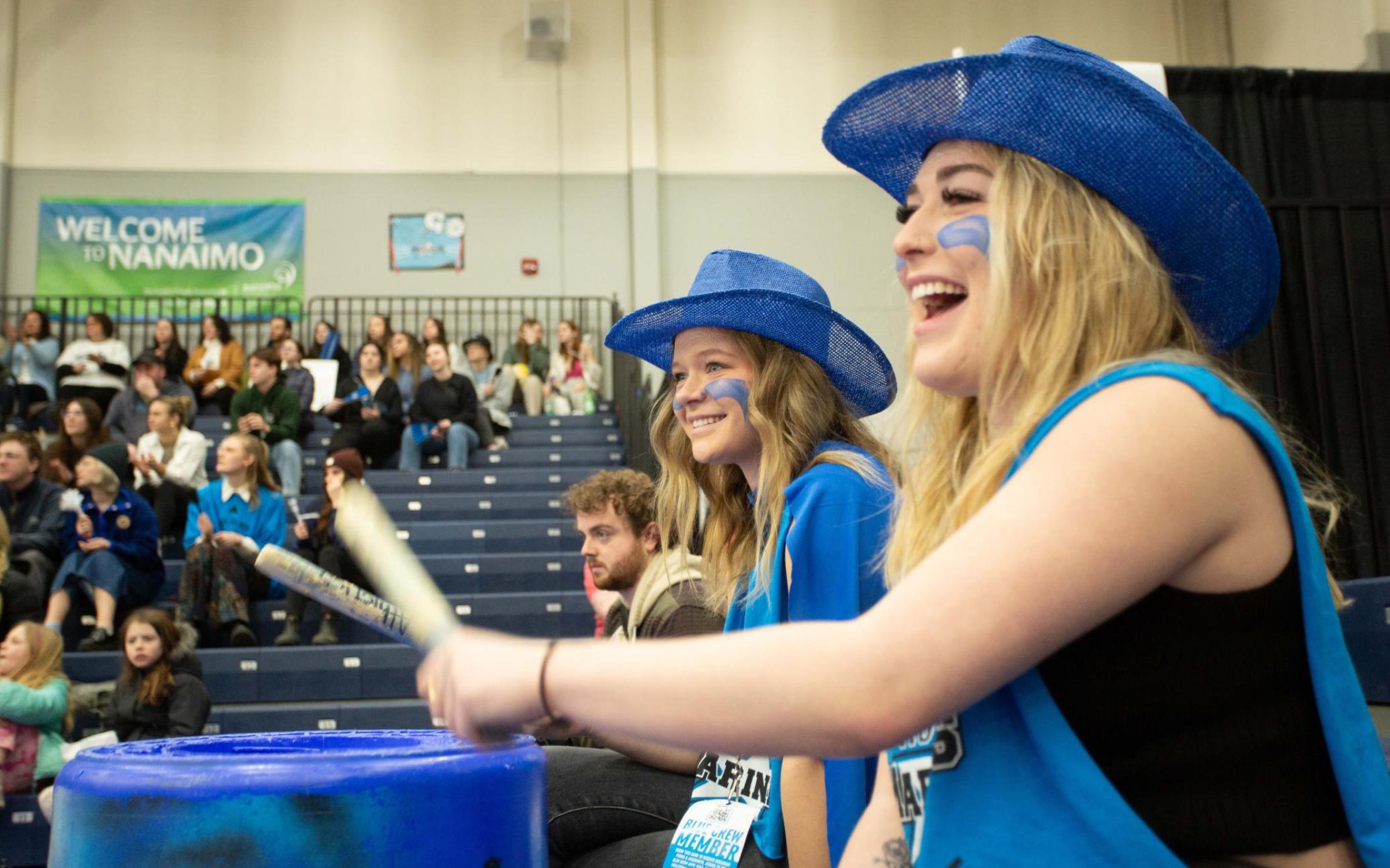 Women wearing blue bang on drums
