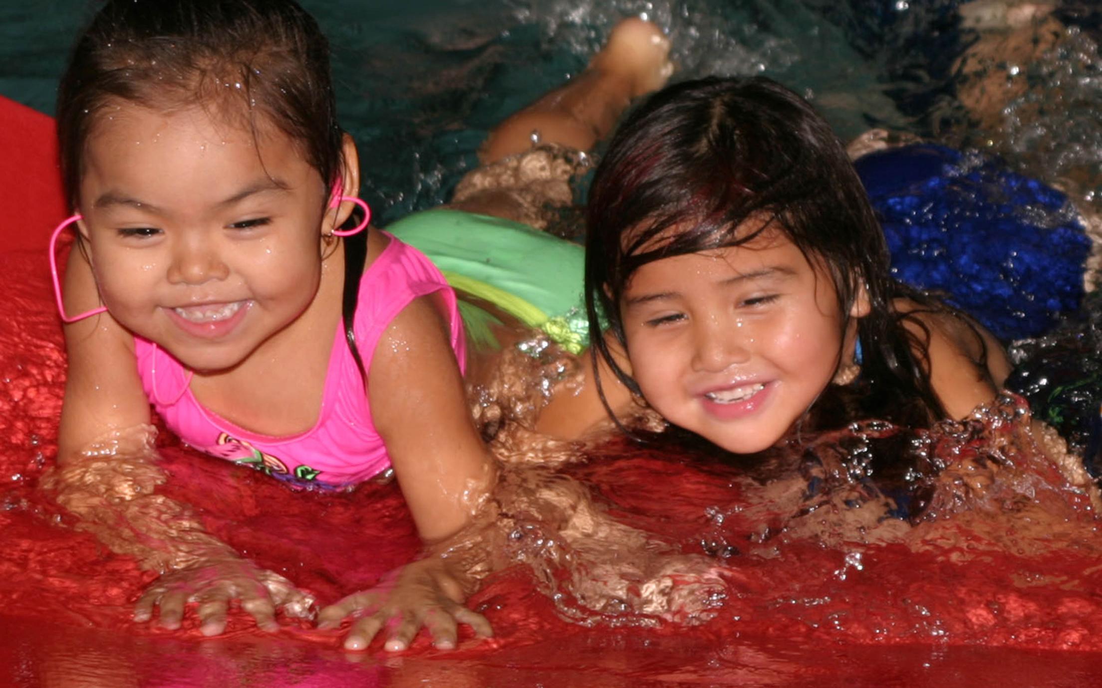 A Child and Youth Care First Nations Worker taking care of two little girls who are having fun at the pool