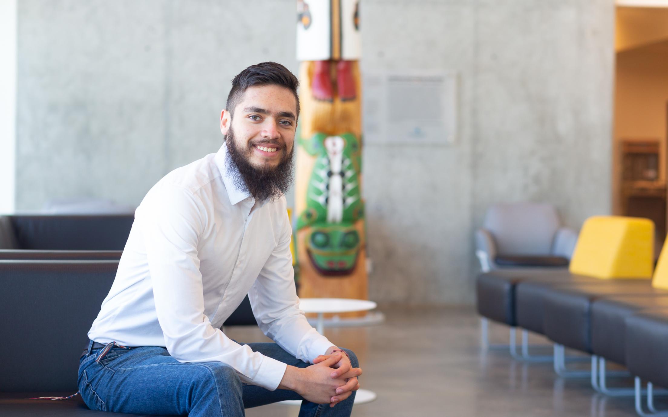 Fernando sits near the totem inside the Centre for Health and Science, VIU's Nanaimo campus