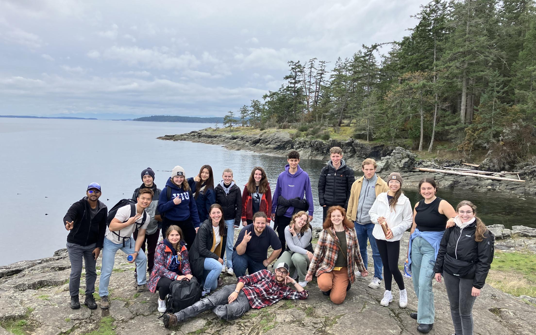 Group photo with a view of the ocean and trees behind them