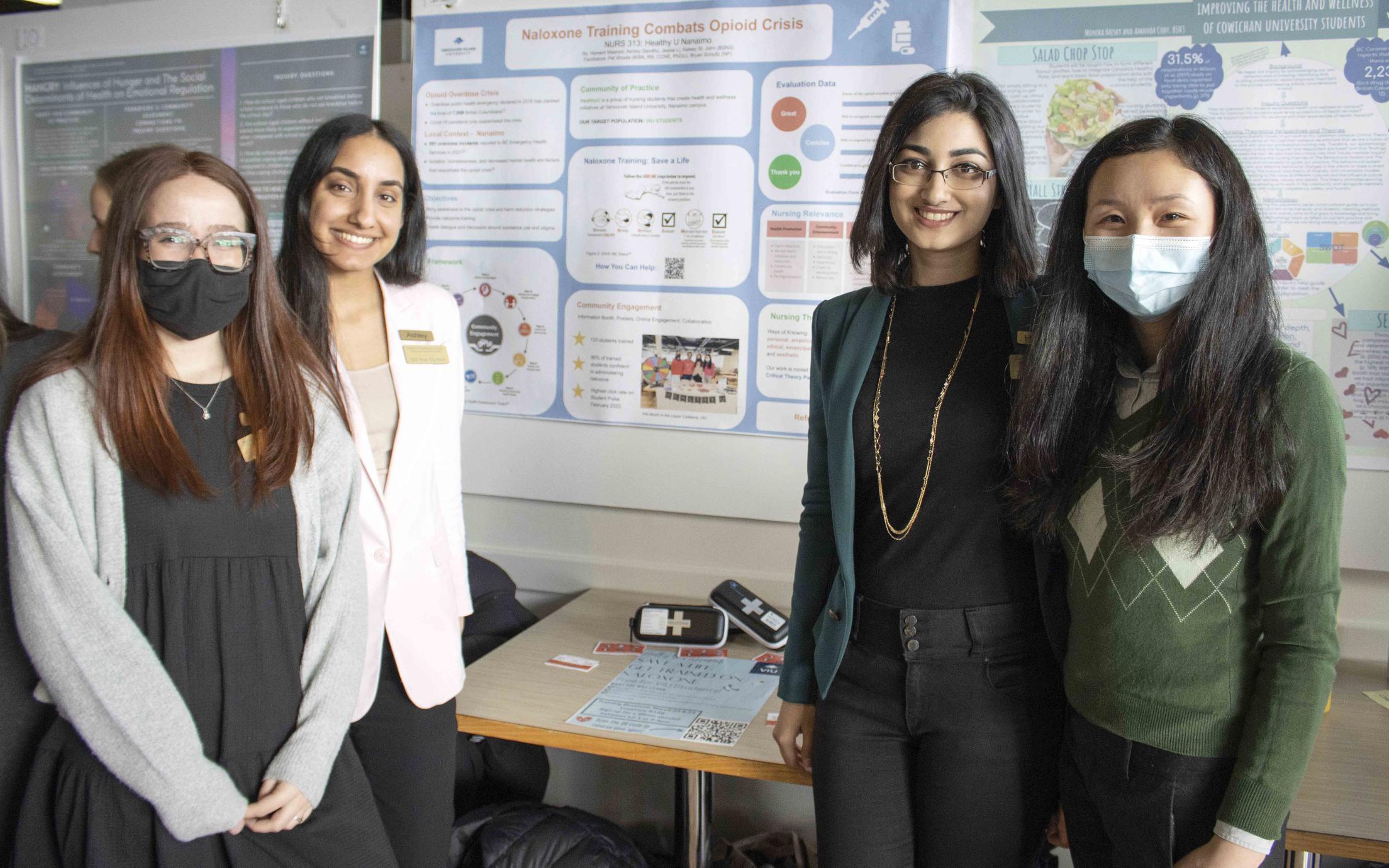 Four students standing in front of a poster