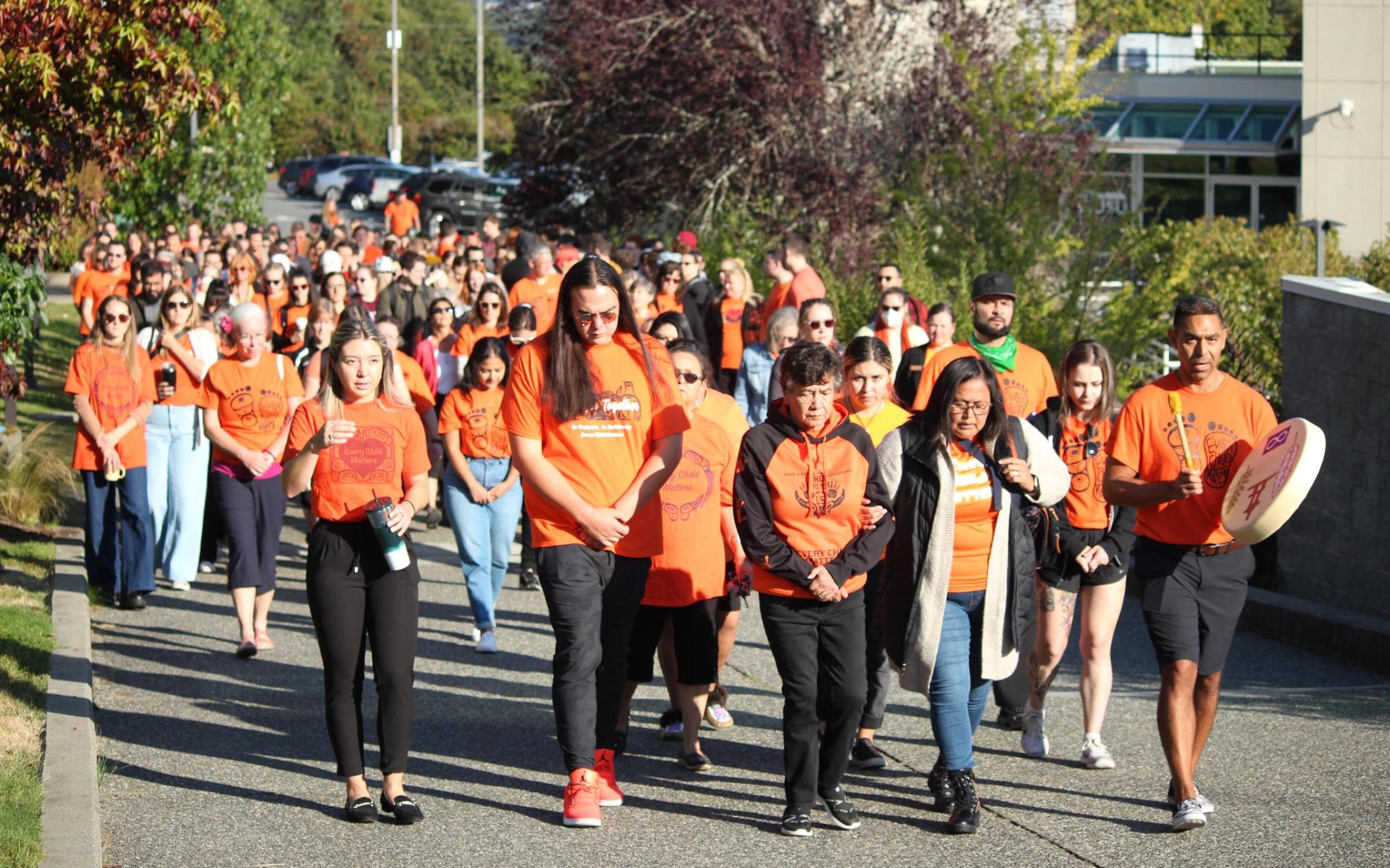 A group of people wearing orange shirts walk together at VIU's Nanaimo campus