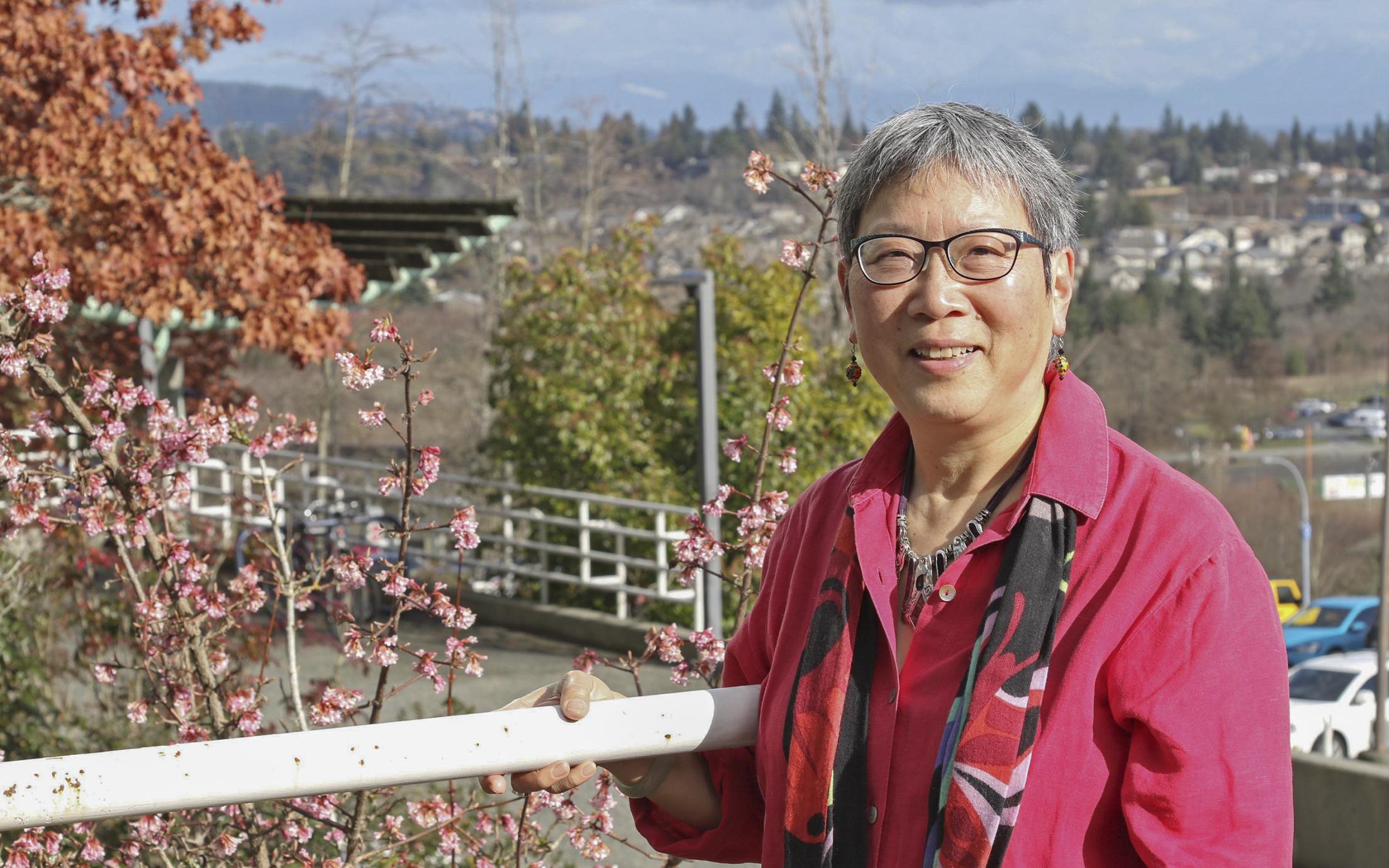 Dr. Imogene Lim stands along a guard rail with the Nanaimo cityscape in the background.