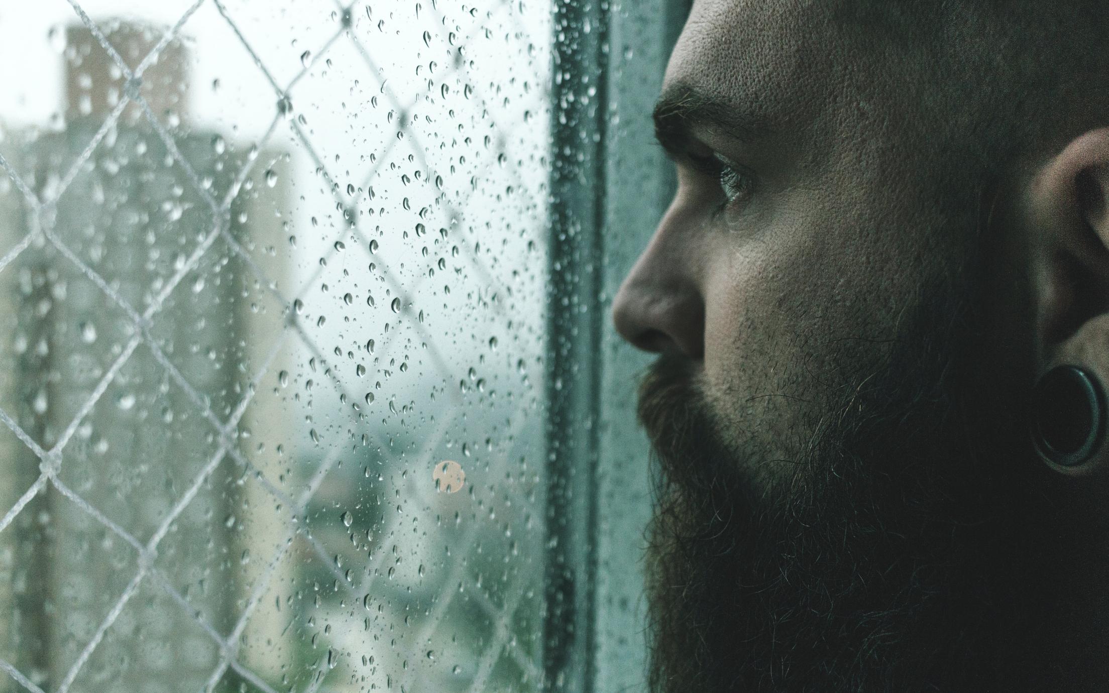Man staring out the window at the rain