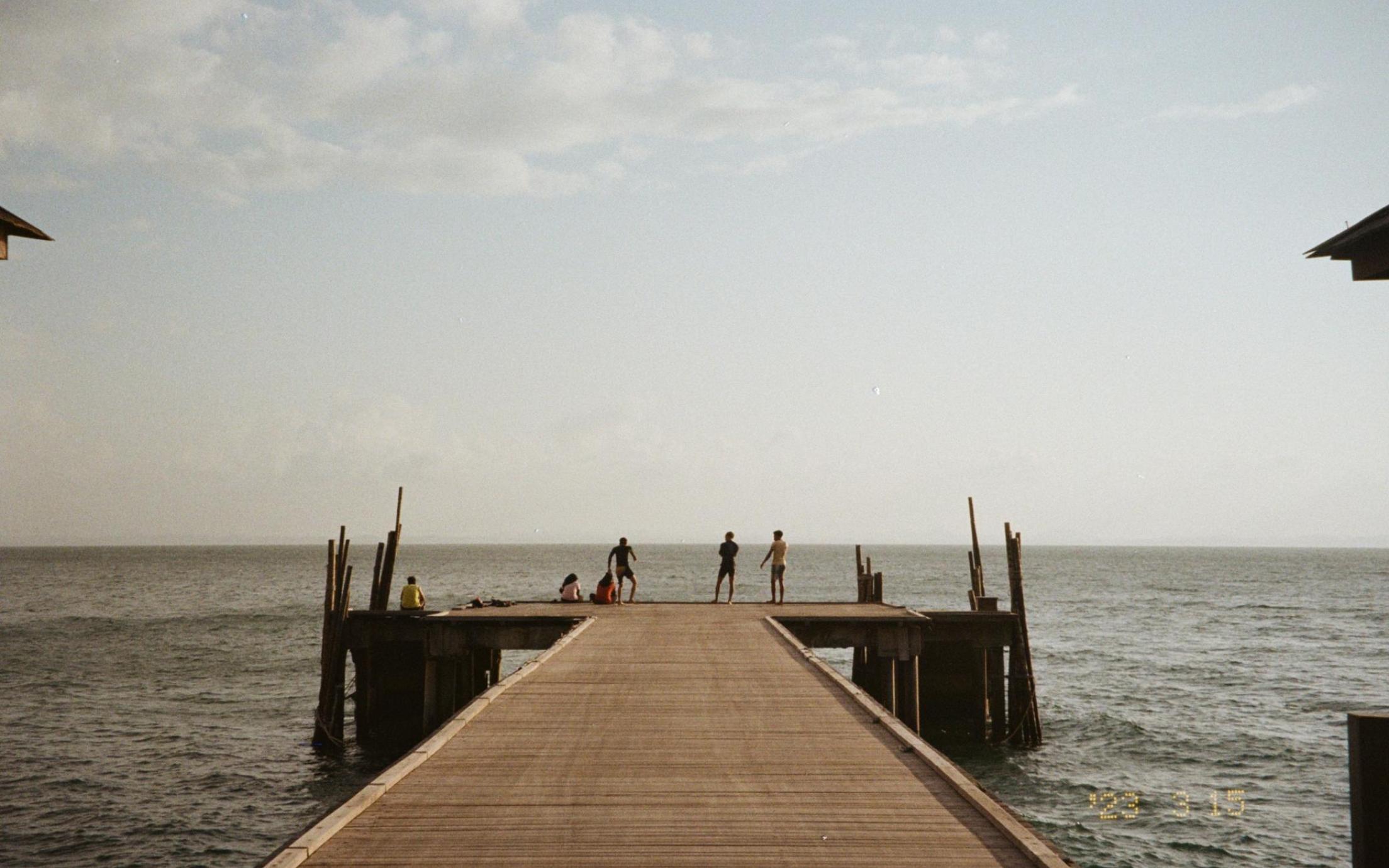 A dock with people on it, ocean behind