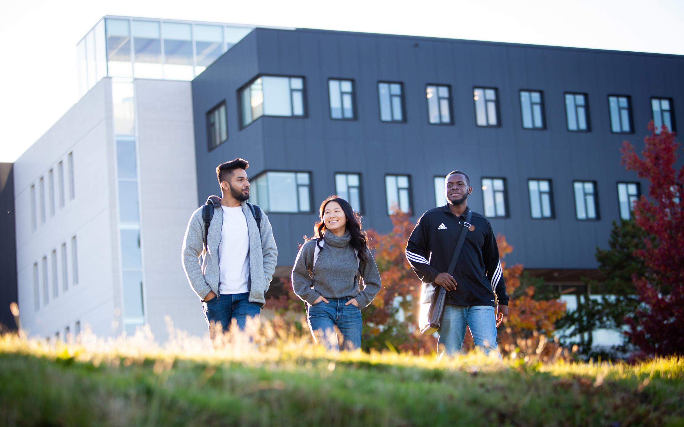 Three VIU students walk on a grassy hill at the Nanaimo Campus.