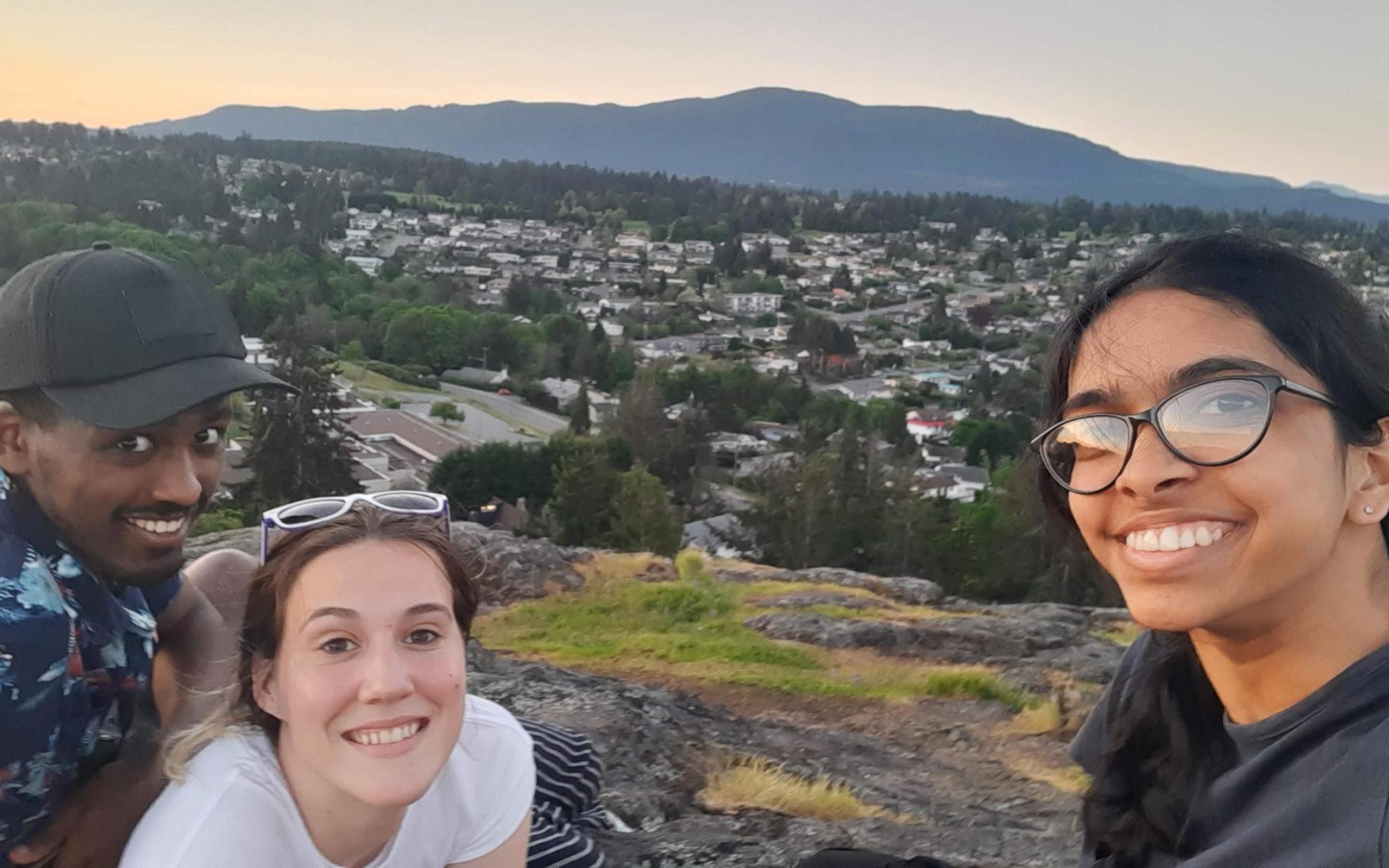 three students pose with the city of Nanaimo in the background