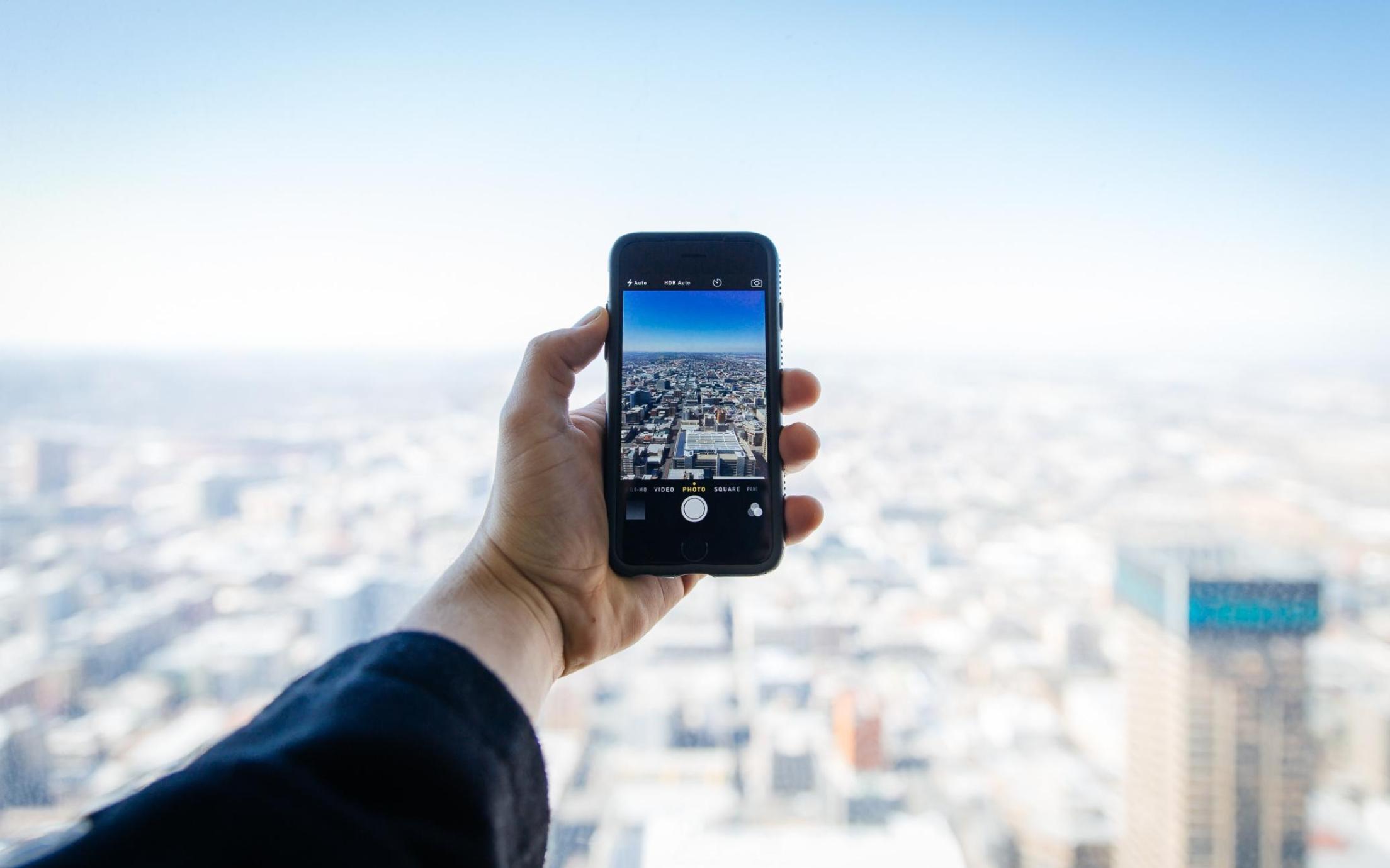 person holding cellphone out to take a picture of a city view