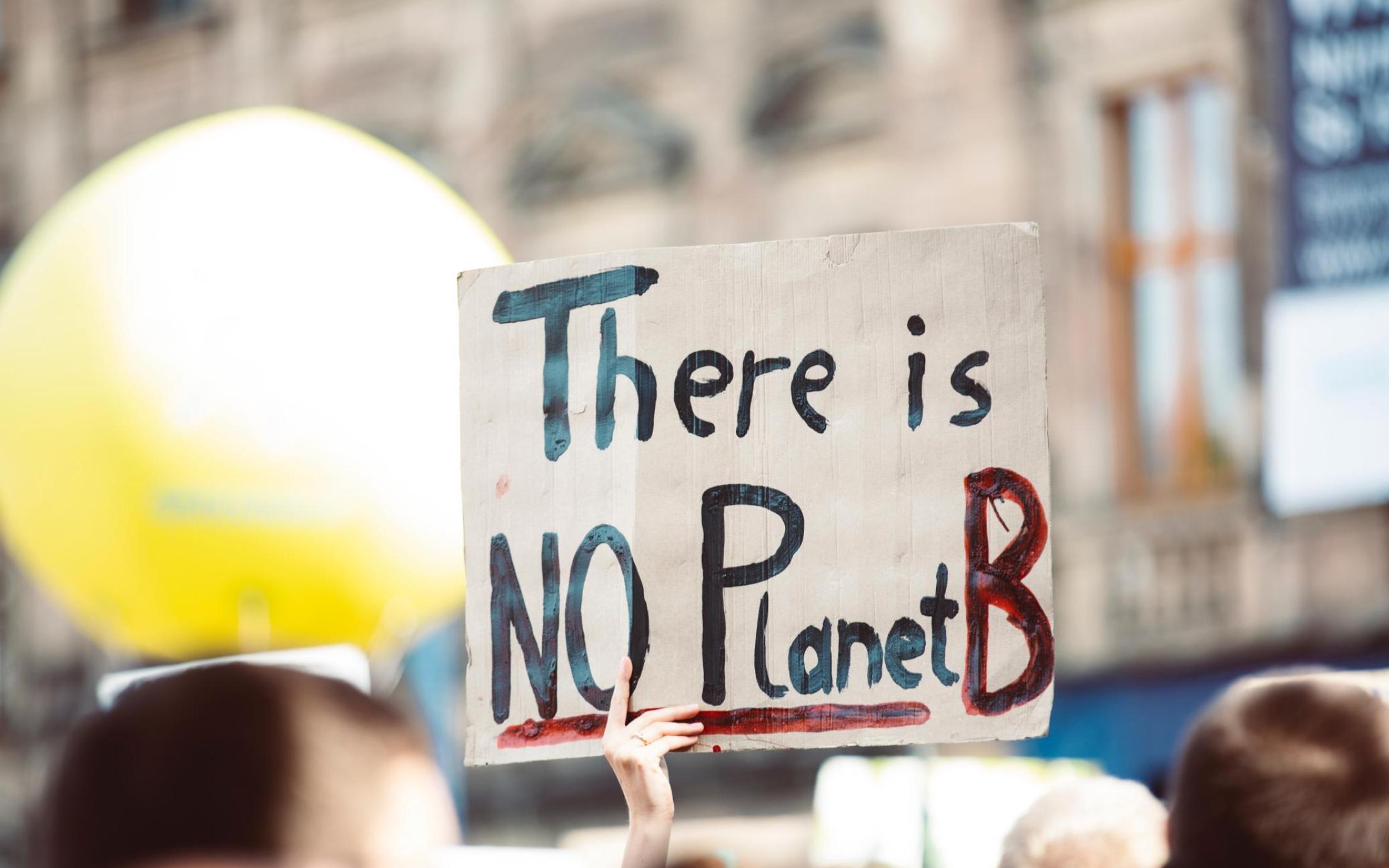 Hands holding a sign that reads: There is no Planet B