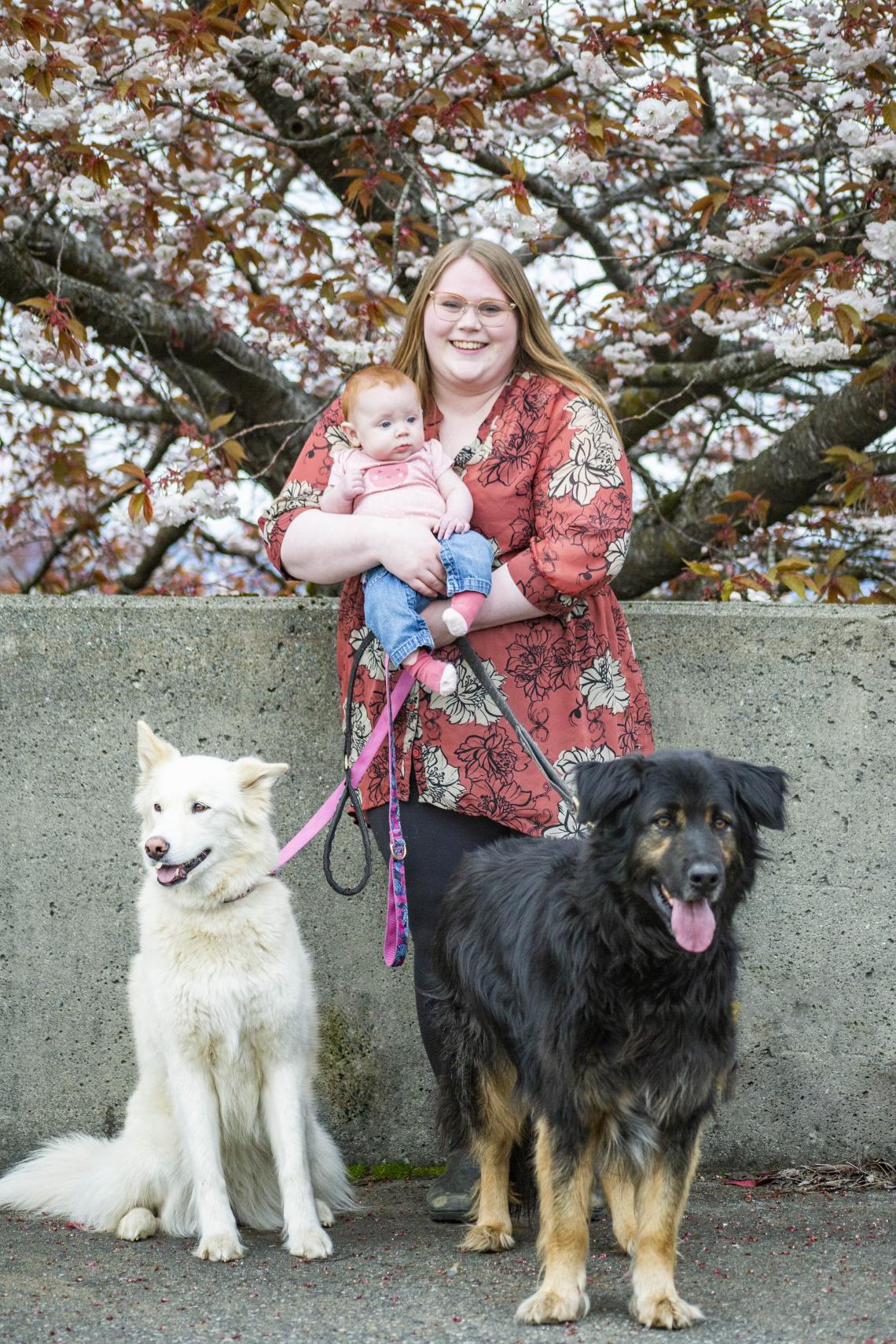 Amy with a baby in her arms and her two dogs
