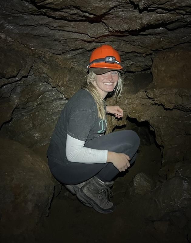 Aiden Kilcommons wears an orange hardhat while exploring a cave.