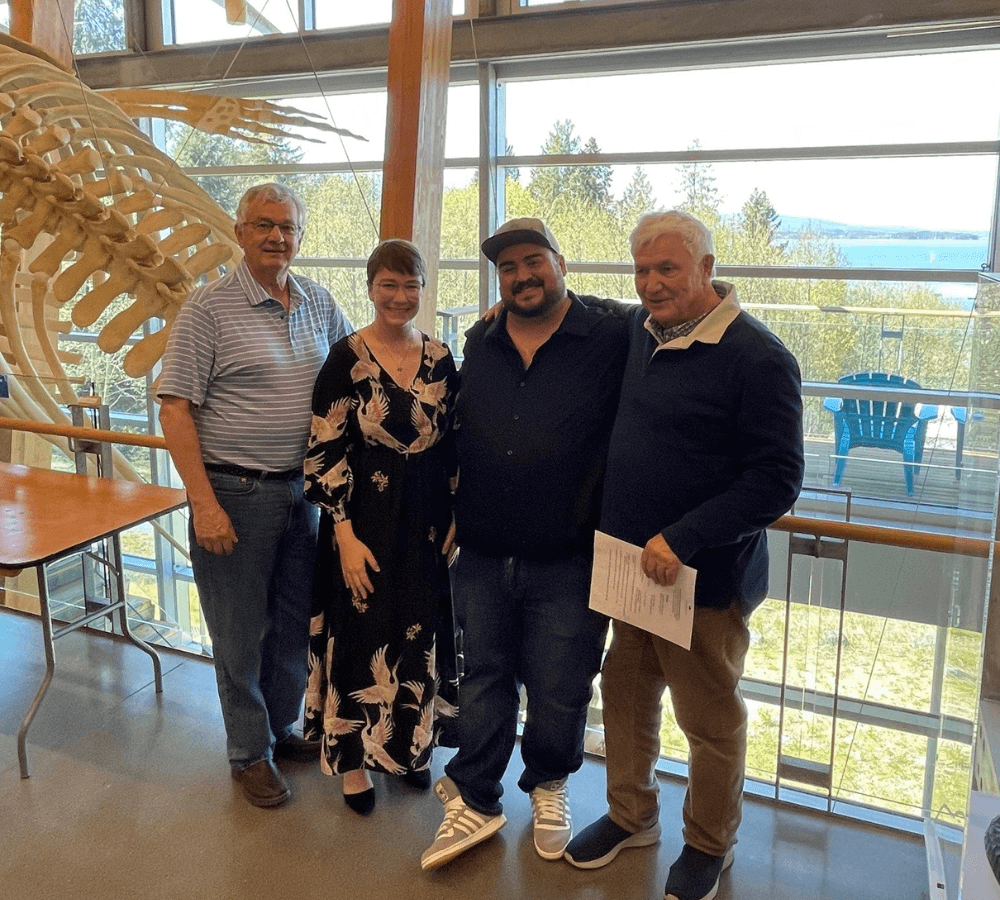 Four people stand next to a whale skeleton