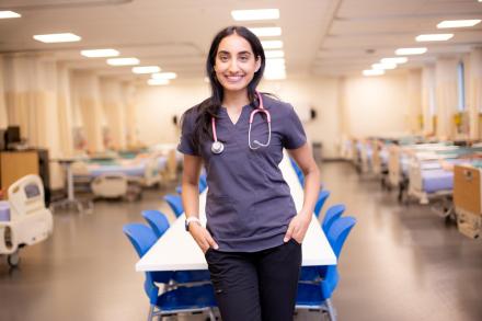 Ashley stands in VIU's nursing simulation lab, wearing scrubs and a stethoscope