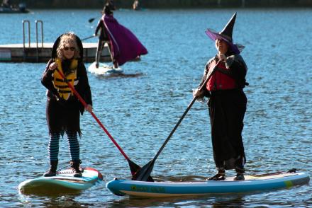 Two women dressed as witches paddle on Westwood Lake