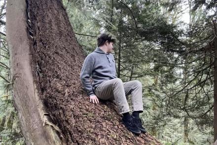 Ethan Hummel sits on a tree trunk.
