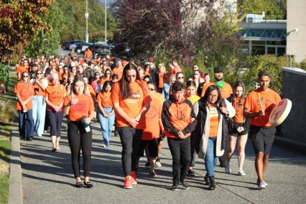 A group of people wearing orange shirts walk together at VIU's Nanaimo campus