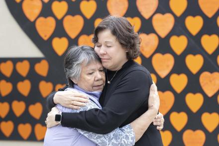 President Saucier and Auntie Geraldine hug in front of a wall of orange hearts
