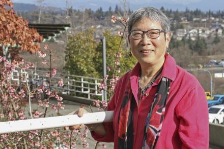 Dr. Imogene Lim stands along a guard rail with the Nanaimo cityscape in the background.