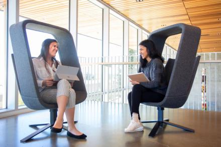 Two students interact while sitting in chairs