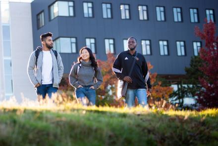 Three VIU students walk on a grassy hill at the Nanaimo Campus.
