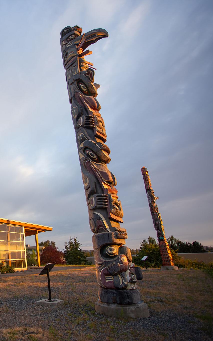 Totem pole in front of a building bathed in sunshine.