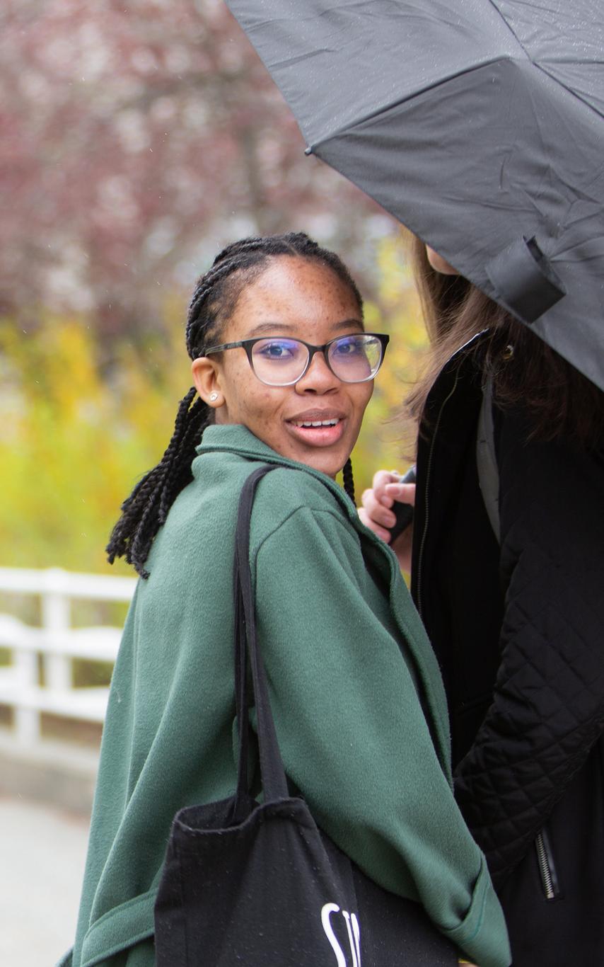 A young woman sharing an umbrella with another person.