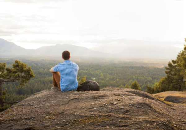 A person sitting on a mountaintop looking out at the view. 