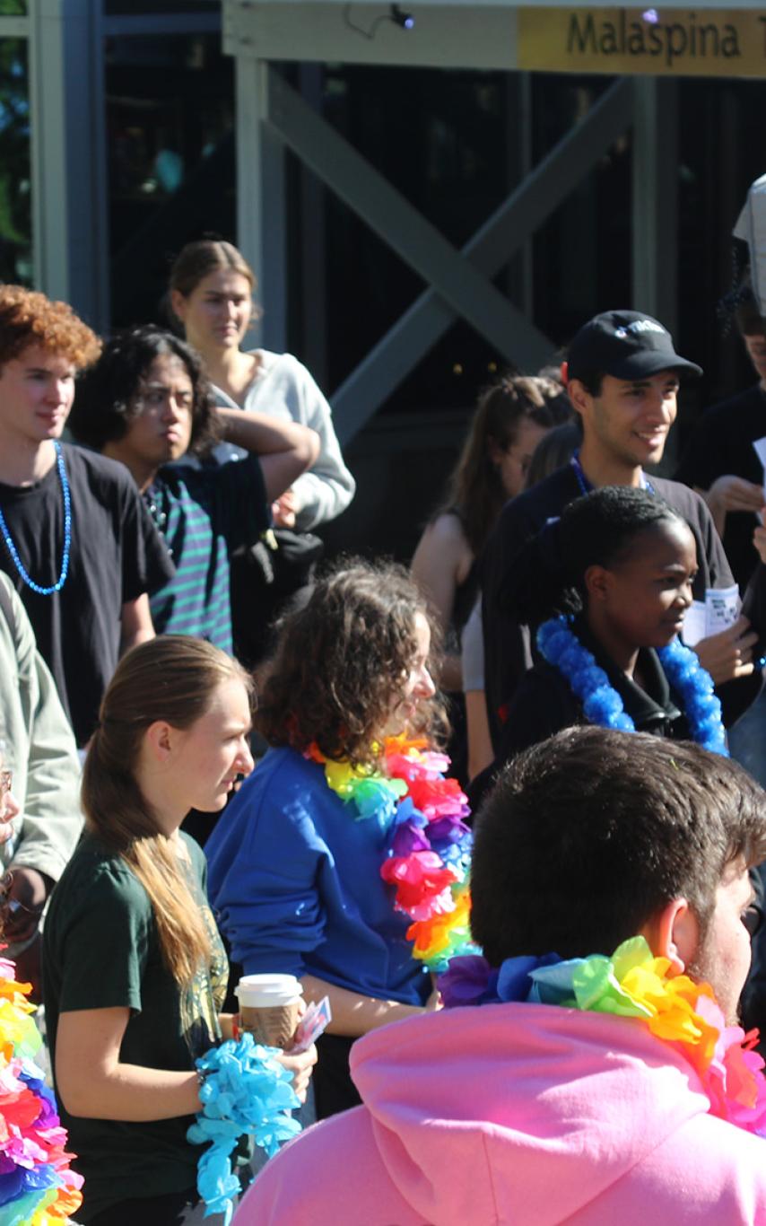 Group of people at an event outside. Some are wearing leis